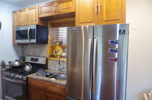 kitchen featuring tasteful backsplash, sink, dark stone counters, and appliances with stainless steel finishes