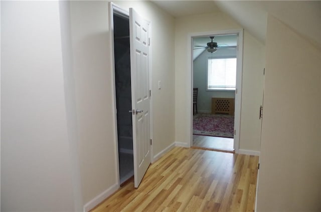 corridor with light hardwood / wood-style flooring and vaulted ceiling