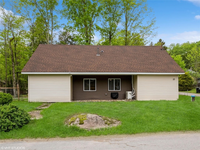 back of property featuring roof with shingles and a yard