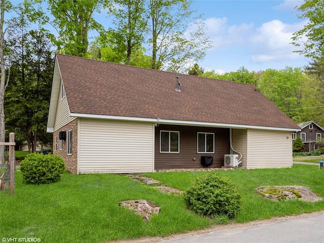 rear view of house featuring roof with shingles, a lawn, a cooling unit, and brick siding