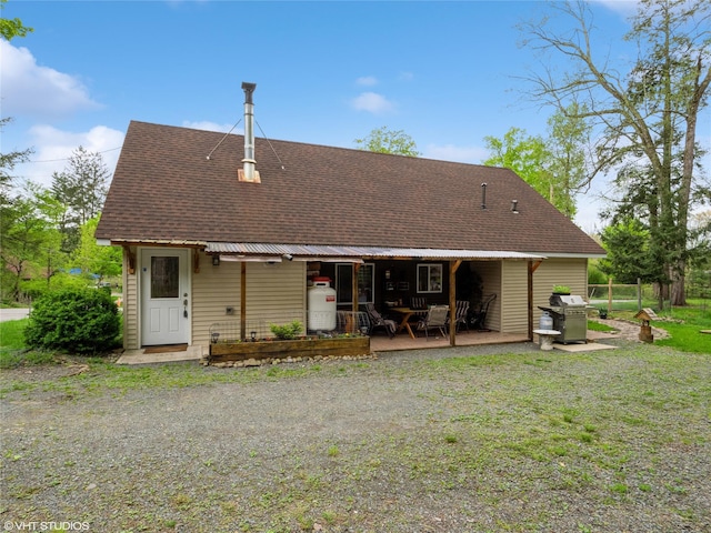 rear view of house featuring roof with shingles and covered porch