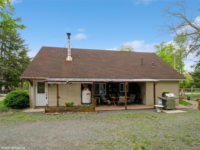 rear view of house featuring a shingled roof and covered porch
