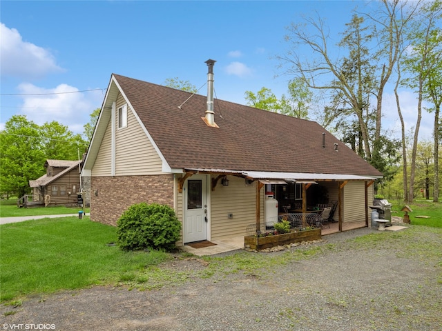 rear view of property featuring a lawn, roof with shingles, and brick siding