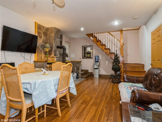 dining space featuring wood finished floors, stairs, a wood stove, and recessed lighting