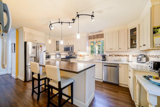 kitchen featuring decorative backsplash, appliances with stainless steel finishes, dark wood-type flooring, sink, and a kitchen island