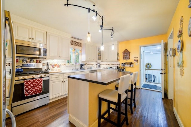 kitchen featuring white cabinetry, a center island, dark wood-type flooring, and appliances with stainless steel finishes