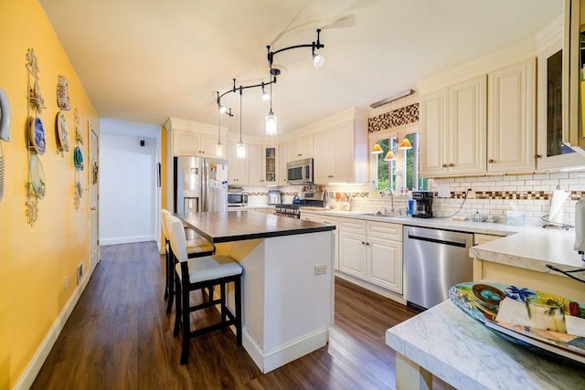 kitchen featuring sink, hanging light fixtures, dark hardwood / wood-style floors, a kitchen island, and stainless steel appliances