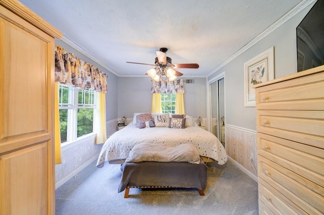 carpeted bedroom featuring ceiling fan, crown molding, and a closet