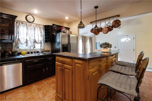 kitchen with stainless steel appliances, sink, light tile patterned floors, pendant lighting, and a center island