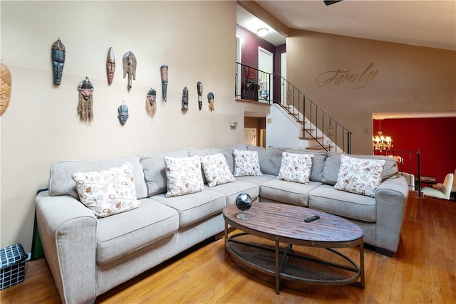 living room featuring hardwood / wood-style floors, vaulted ceiling, and a notable chandelier