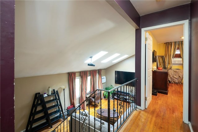 hall with wood-type flooring and vaulted ceiling