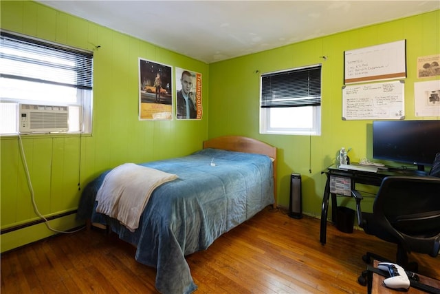 bedroom featuring baseboard heating, hardwood / wood-style floors, and cooling unit