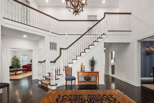 foyer with a notable chandelier, dark wood-type flooring, and a high ceiling