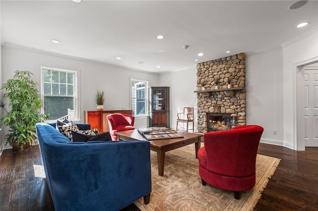 living room with dark hardwood / wood-style flooring, a stone fireplace, and crown molding