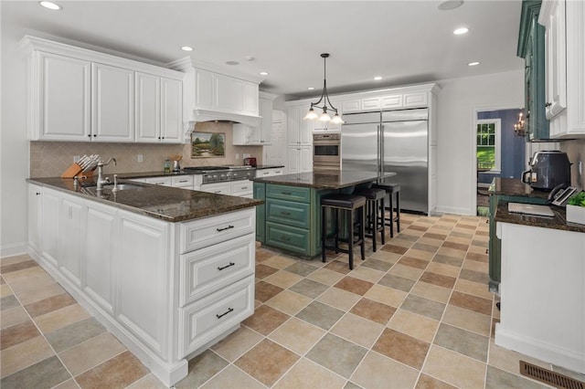 kitchen featuring decorative backsplash, stainless steel appliances, sink, white cabinets, and a kitchen island