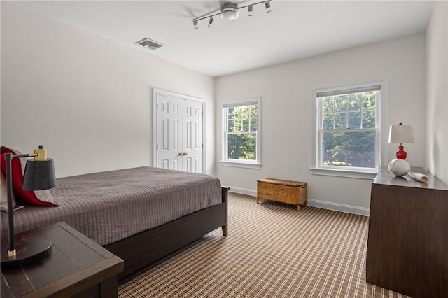 carpeted bedroom with ceiling fan and rail lighting