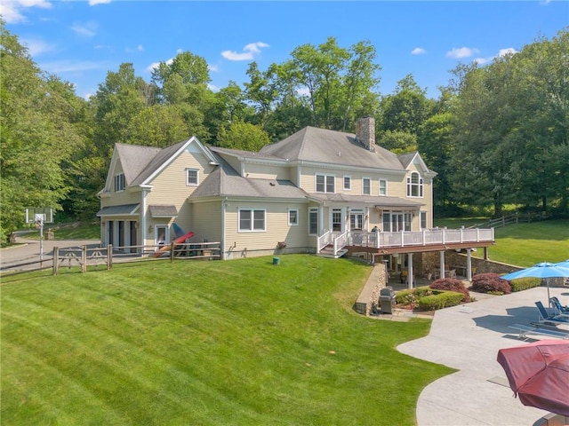 back of property featuring a lawn, a deck, and a patio