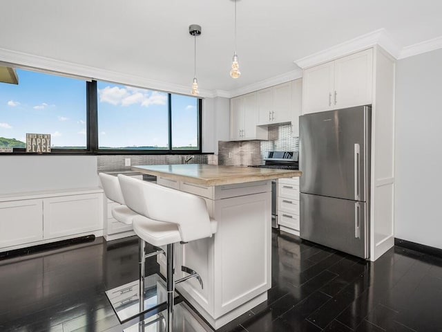 kitchen with white cabinets, hanging light fixtures, ornamental molding, tasteful backsplash, and stainless steel appliances