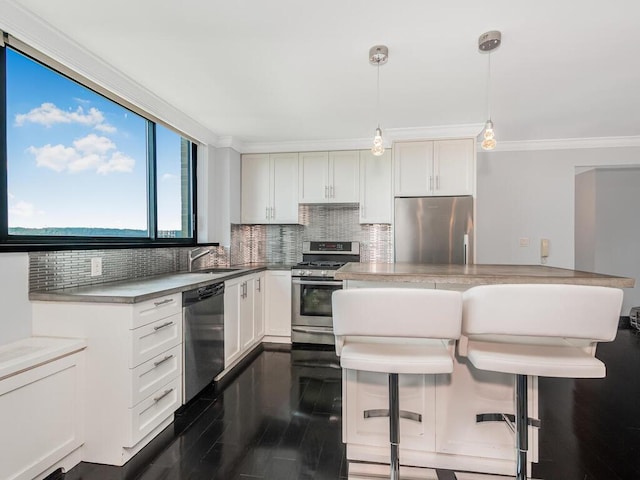 kitchen with pendant lighting, white cabinets, appliances with stainless steel finishes, and tasteful backsplash