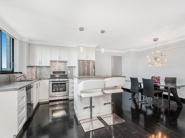 kitchen with stainless steel appliances, sink, decorative light fixtures, dark hardwood / wood-style floors, and white cabinetry