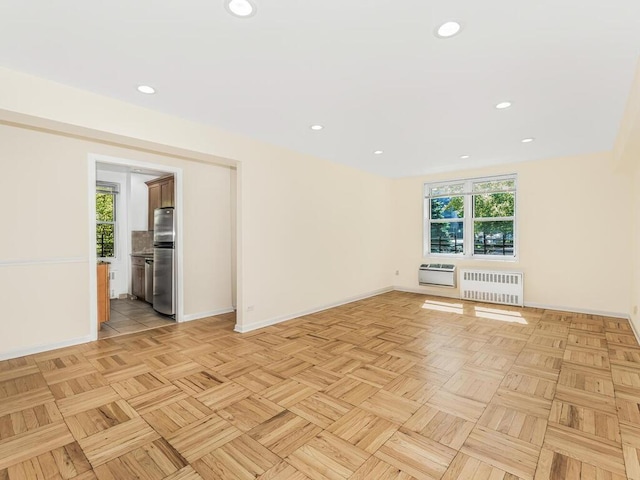 unfurnished living room featuring heating unit, radiator heating unit, and light parquet flooring