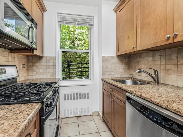 kitchen with radiator, light stone counters, and stainless steel appliances