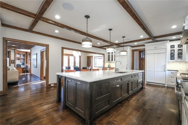 kitchen with a large island, sink, dark wood-type flooring, tasteful backsplash, and pendant lighting