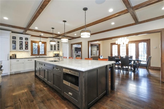 kitchen with white cabinets, sink, dark hardwood / wood-style floors, and an island with sink