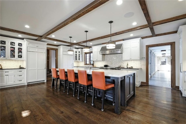 kitchen featuring pendant lighting, wall chimney exhaust hood, dark hardwood / wood-style floors, and backsplash