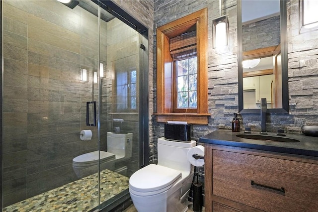 bathroom featuring a shower with door, vanity, tile walls, and toilet