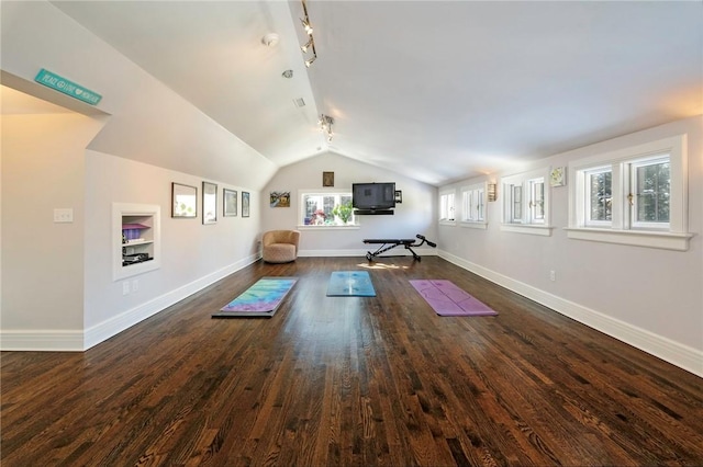 exercise room featuring rail lighting, dark wood-type flooring, plenty of natural light, and lofted ceiling