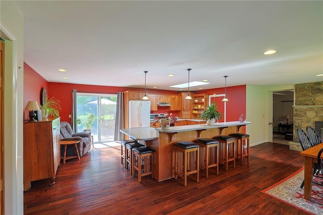 kitchen with a kitchen breakfast bar, white refrigerator, dark hardwood / wood-style floors, a fireplace, and decorative light fixtures