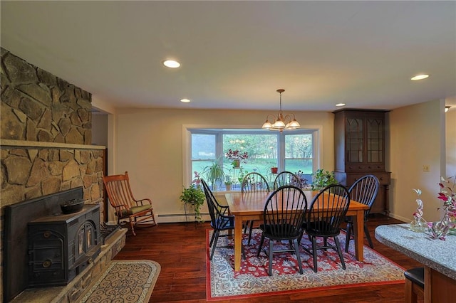 dining space featuring a wood stove, dark hardwood / wood-style flooring, a baseboard radiator, and an inviting chandelier