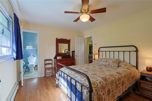 bedroom with baseboard heating, ensuite bath, ceiling fan, and wood-type flooring