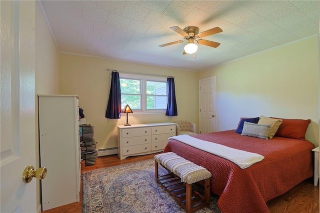 bedroom featuring wood-type flooring, a baseboard heating unit, ceiling fan, and crown molding