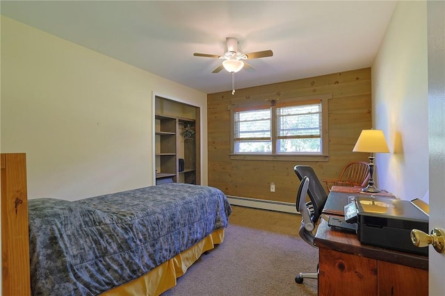 carpeted bedroom with ceiling fan, a closet, wooden walls, and a baseboard radiator