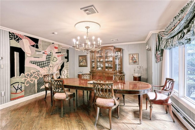 dining space featuring hardwood / wood-style floors, ornamental molding, a baseboard radiator, and a chandelier