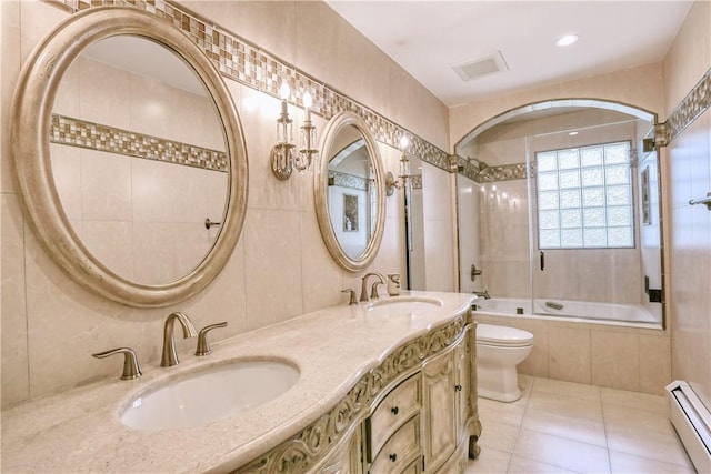 full bathroom with tile patterned floors, tiled shower / bath combo, toilet, baseboard heating, and tile walls