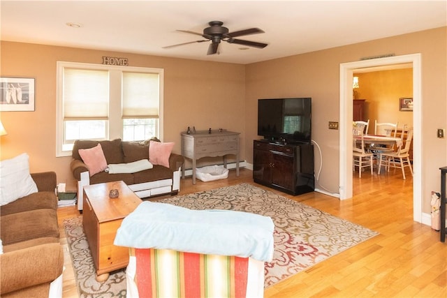 living room with hardwood / wood-style flooring, ceiling fan, and a baseboard heating unit