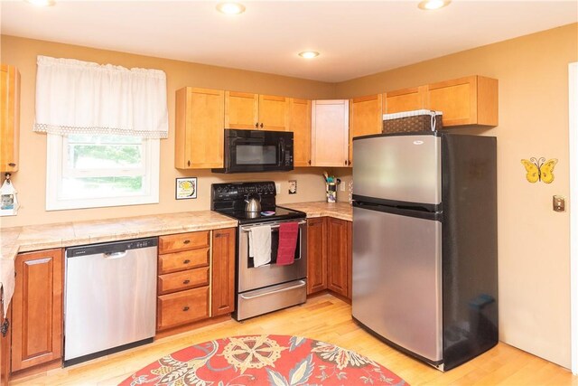 kitchen with light hardwood / wood-style floors, stainless steel appliances, and light brown cabinets