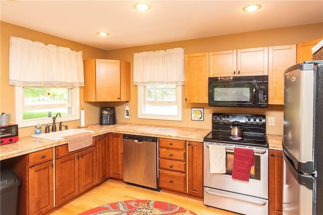 kitchen featuring stainless steel appliances, plenty of natural light, light hardwood / wood-style floors, and sink