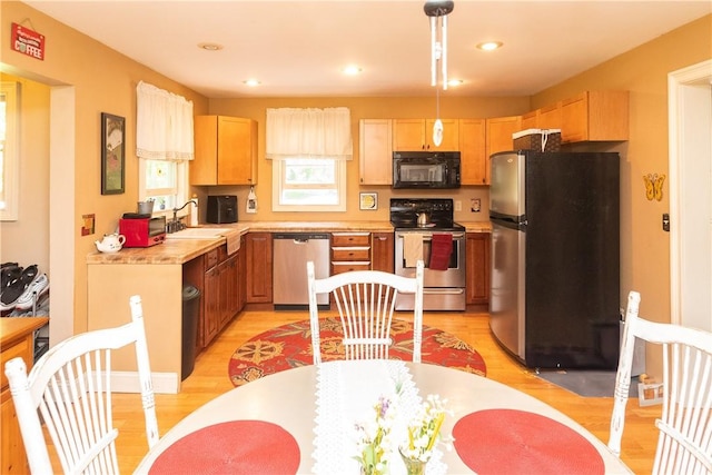 kitchen featuring sink, light brown cabinets, stainless steel appliances, light hardwood / wood-style floors, and decorative light fixtures