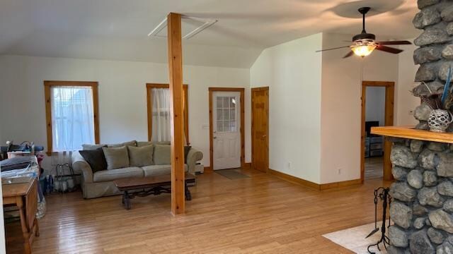 living room featuring vaulted ceiling, light hardwood / wood-style flooring, and ceiling fan