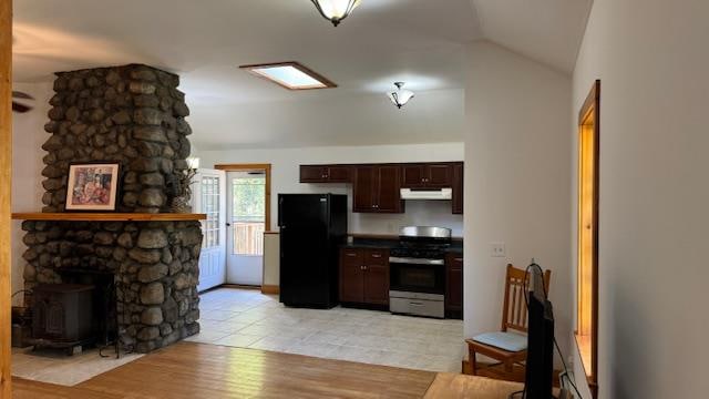 kitchen featuring black fridge, vaulted ceiling, light hardwood / wood-style flooring, stainless steel gas stove, and dark brown cabinets