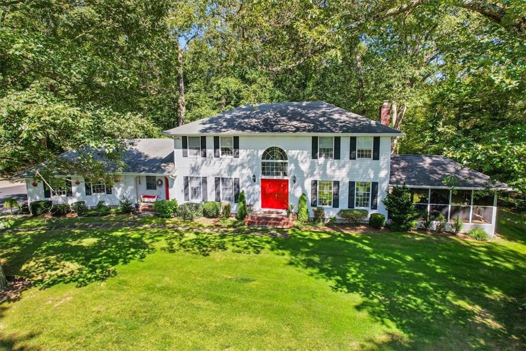 colonial home with a sunroom and a front yard