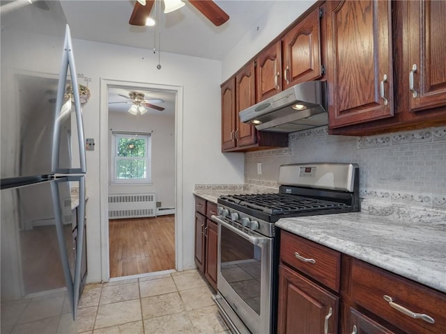 kitchen with backsplash, ceiling fan, appliances with stainless steel finishes, light stone counters, and radiator heating unit