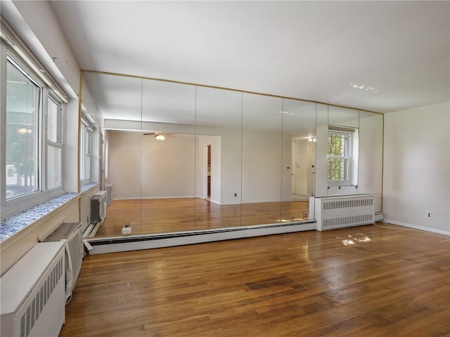 spare room with baseboard heating, radiator, dark wood-type flooring, and ceiling fan