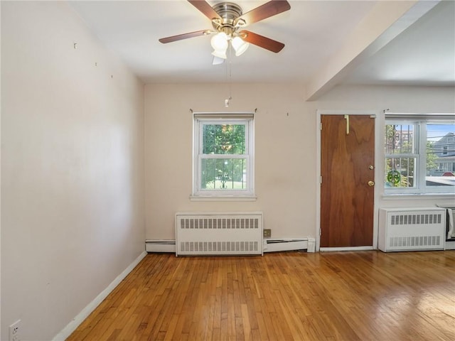 unfurnished room featuring a wealth of natural light, light wood-type flooring, and radiator