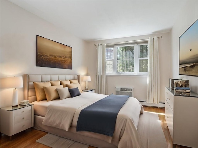 bedroom featuring a wall mounted air conditioner, light hardwood / wood-style floors, and baseboard heating