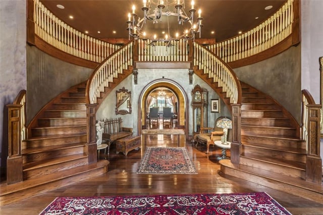 foyer featuring a chandelier, wood-type flooring, and a towering ceiling